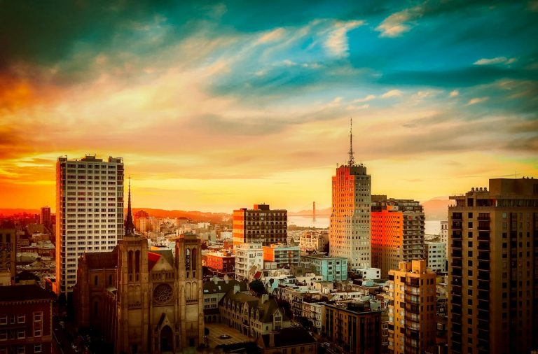 Stunning view of San Francisco cityscape with Golden Gate Bridge at sunset, vibrant urban atmosphere.